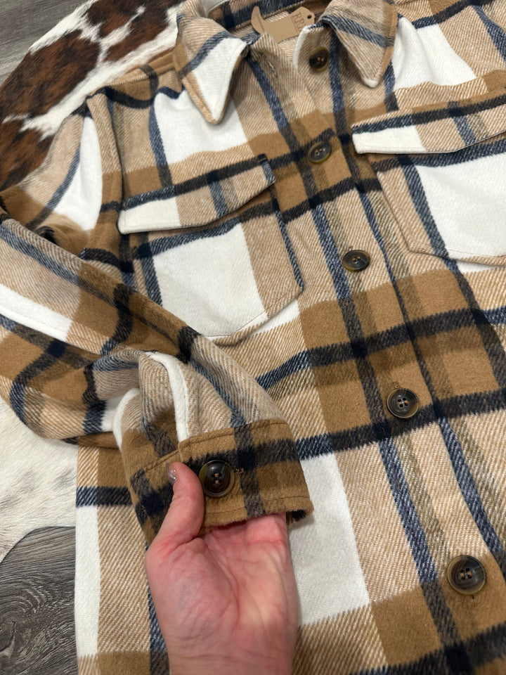 The Athens Camel Plaid Flannel Jacket features a relaxed, oversized fit with classic details, including a collared neckline, chest flap pockets, and convenient side pockets. Crafted from cozy flannel fabric, this jacket is perfect for layering on cooler days. Available in sizes small (3-5), medium (6-8), and large (9-11); if between sizes, sizing down is recommended. Comparable to shackets by Carhartt and Abercrombie, this jacket combines rugged style with warmth and comfort for everyday wear.
