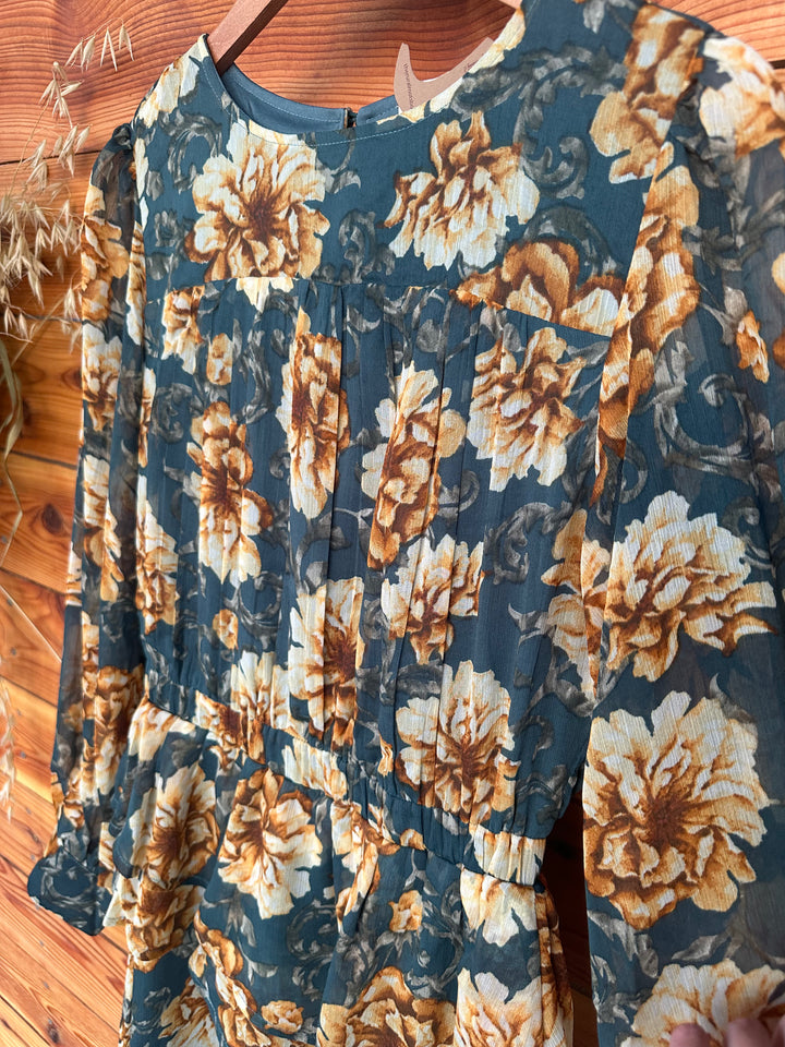 Beautiful The Lola teal layered skirt floral chiffon dress with a round neck and keyhole back featuring a button closure. Long sleeves with buttoned cuffs and pleated shoulders add elegance, while the elastic waist ensures a flattering fit. Fully lined and crafted from 100% polyester, available in Small (3-5), Medium (6-8), and Large (9-11). Perfect for weddings or special events, competing with styles from Lulus and Dressbarn.