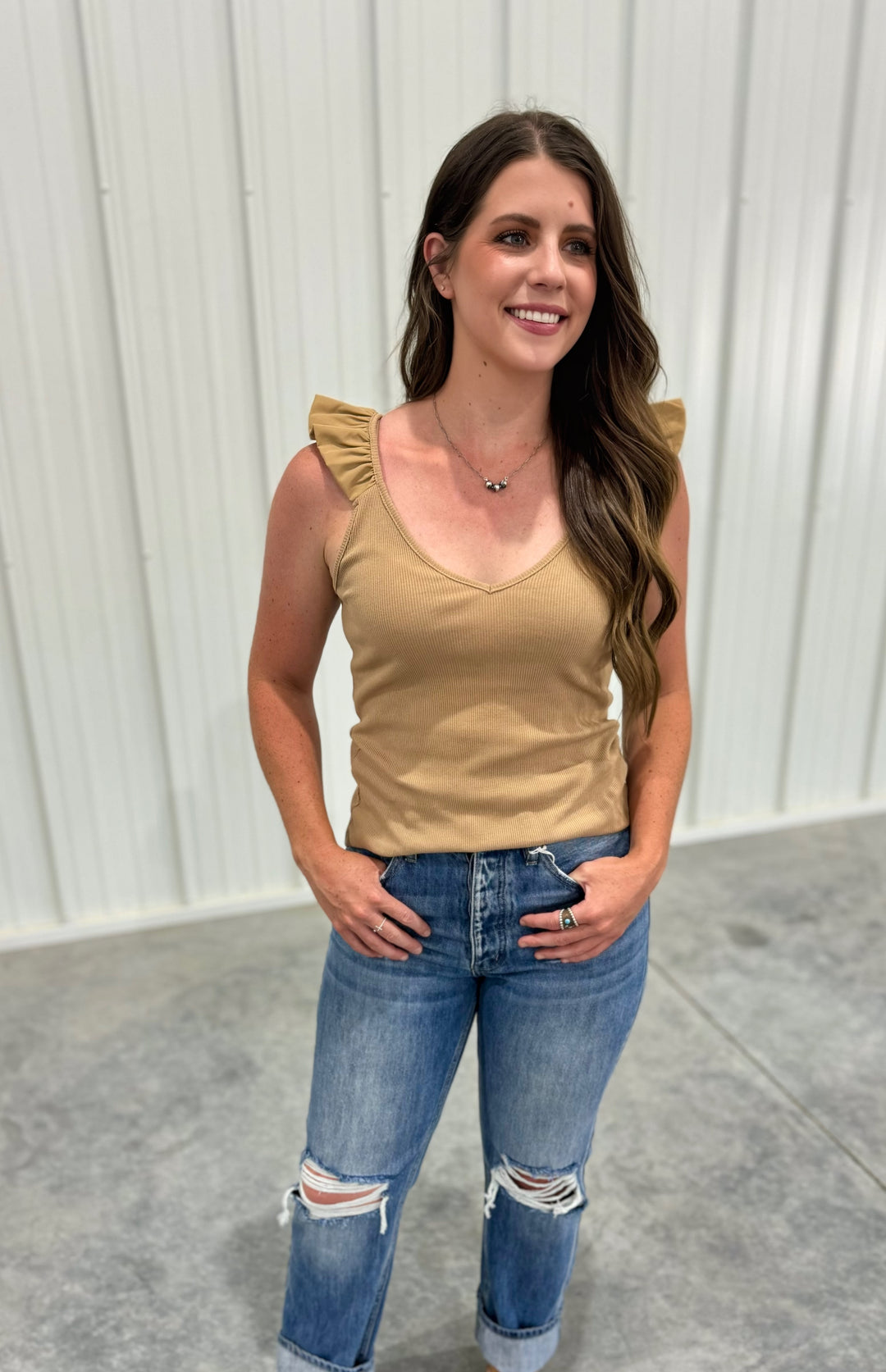 The Ashland Ruffle Tank Top in a warm mocha shade is crafted from 100% breathable cotton, offering a lightweight and comfortable feel for casual, everyday style. This women’s sleeveless blouse features delicate ruffle accents, adding a touch of femininity to a relaxed fit. Available in sizes small (2-4), medium (6-8), and large (8-10), this top is a versatile wardrobe staple, perfect for layering or wearing solo, and is comparable to tops from Madewell and Aerie.