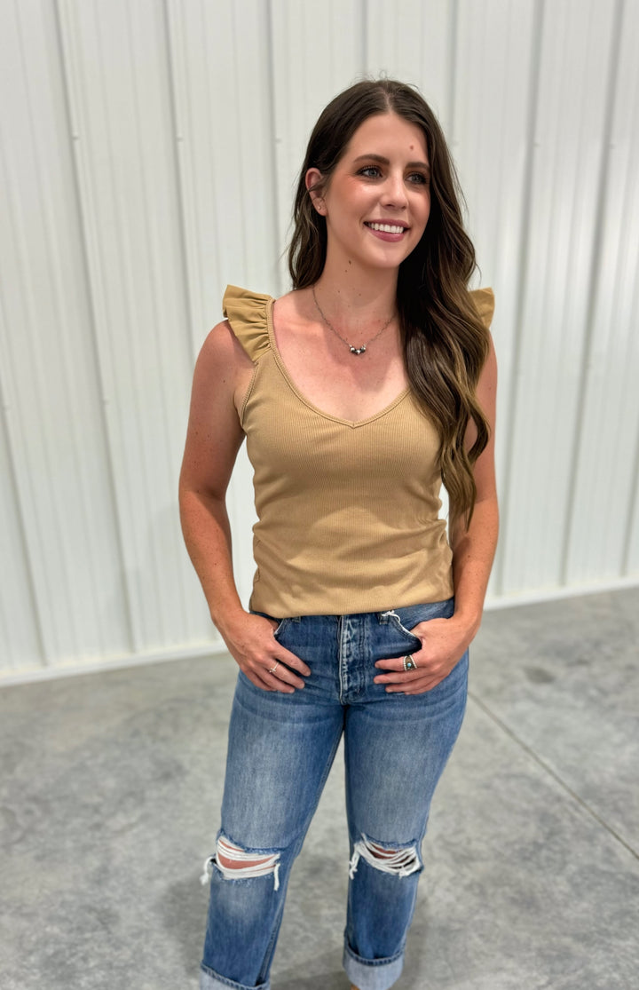 The Ashland Ruffle Tank Top in a warm mocha shade is crafted from 100% breathable cotton, offering a lightweight and comfortable feel for casual, everyday style. This women’s sleeveless blouse features delicate ruffle accents, adding a touch of femininity to a relaxed fit. Available in sizes small (2-4), medium (6-8), and large (8-10), this top is a versatile wardrobe staple, perfect for layering or wearing solo, and is comparable to tops from Madewell and Aerie.
