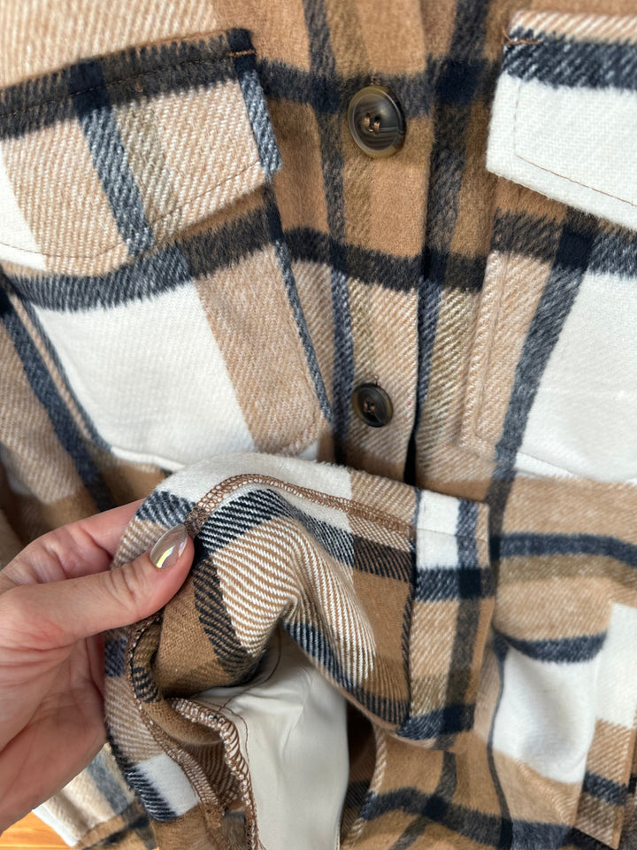 The Athens Camel Plaid Flannel Jacket features a relaxed, oversized fit with classic details, including a collared neckline, chest flap pockets, and convenient side pockets. Crafted from cozy flannel fabric, this jacket is perfect for layering on cooler days. Available in sizes small (3-5), medium (6-8), and large (9-11); if between sizes, sizing down is recommended. Comparable to shackets by Carhartt and Abercrombie, this jacket combines rugged style with warmth and comfort for everyday wear.