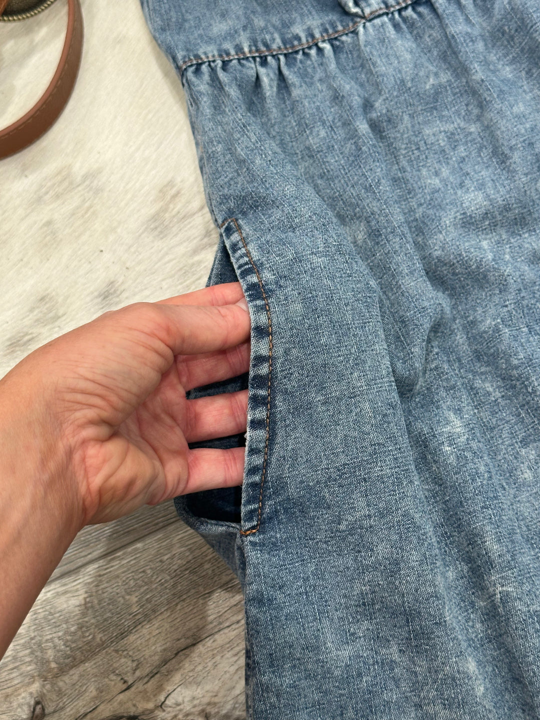 Casual denim babydoll dress with a collared neck, button-up front, and layered ruffle shoulders. Designed in a relaxed fit with lightweight, non-sheer fabric, this dress also features side pockets. Available in sizes Small (3-5), Medium (6-8), and Large (8-11). A comfortable yet stylish option, comparable to designs from ASOS and Forever 21.
