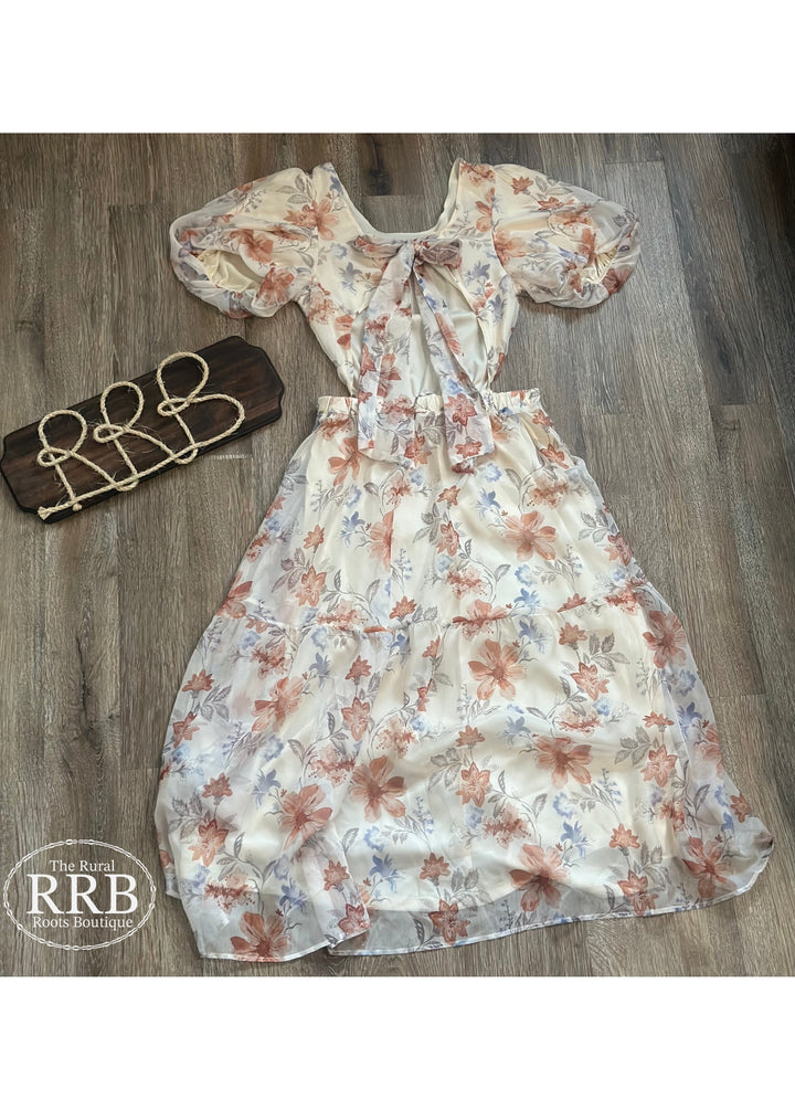 Discover The Little Prairie Dress, an elegant ivory midi dress designed with puff sleeves and a tie-back feature for a flattering fit. The open back adds a chic touch, making it ideal for summer events or casual outings. Crafted from 100% polyester, available in Small (3-5), Medium (6-8), and Large (9-11).