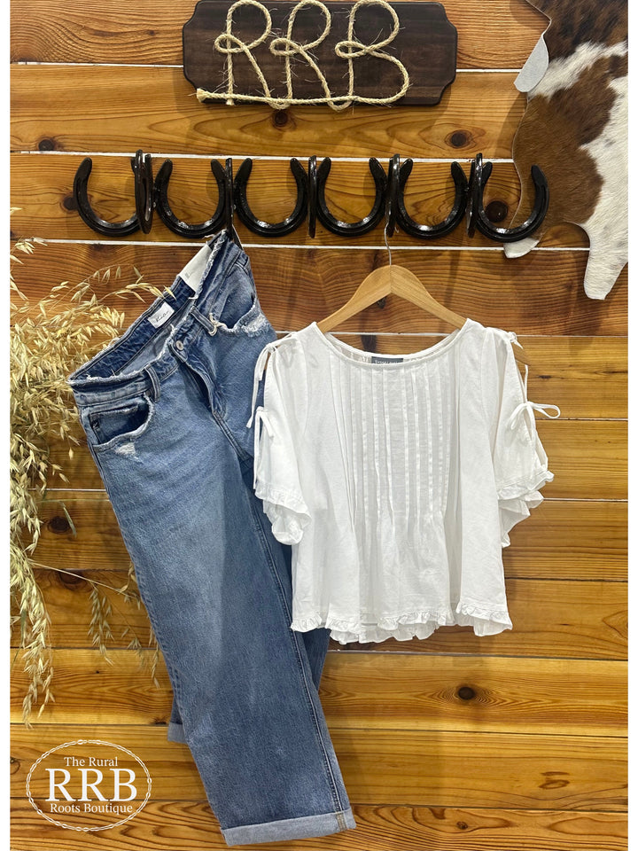 Discover The Linen Shirt, an ivory top featuring a scoop neckline and open tied detailing on the sleeves. With adjustable ties and cut-out detailing, this relaxed-fit top boasts ruffled hems and flutter sleeves for a stylish touch. Made from a soft blend of 45% viscose, 35% linen, and 20% cotton, available in Small (2-4), Medium (6-8), and Large (8-10).