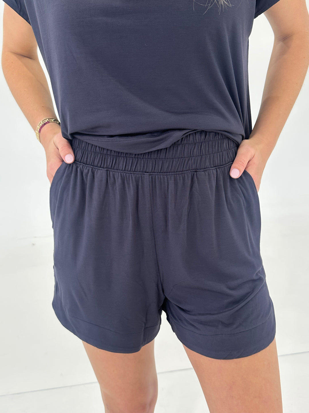 The Holt Shorts in charcoal black feature a high rise fit, elastic waistband, and a flattering tulip scallop side hem. Crafted from ultra-soft viscose modal, these lightweight shorts offer 4-way stretch and moisture-wicking performance, making them ideal for lounging or active days. Side pockets add convenience without sacrificing style.