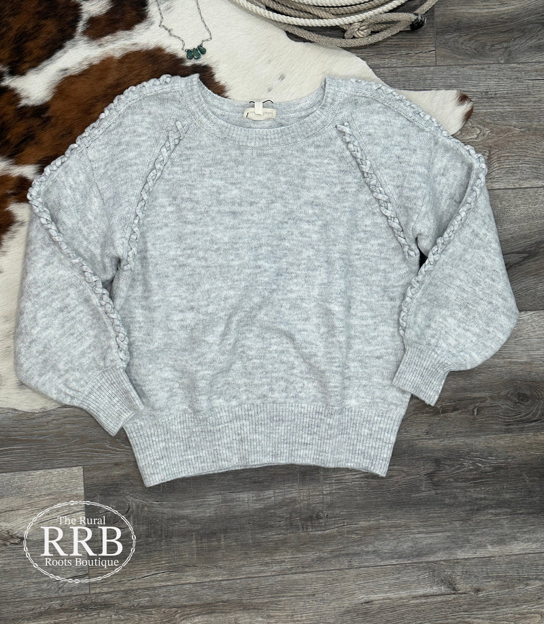 Elevate your wardrobe with the Kimball Braided Detail Sweater in grey. This relaxed-fit knit sweater features unique braided detailing along the top of each sleeve, ensuring comfort and style. Made from 74% acrylic, 22% polyester, and 4% spandex, it's available in sizes Small (3-5), Medium (6-8), and Large (9-11).