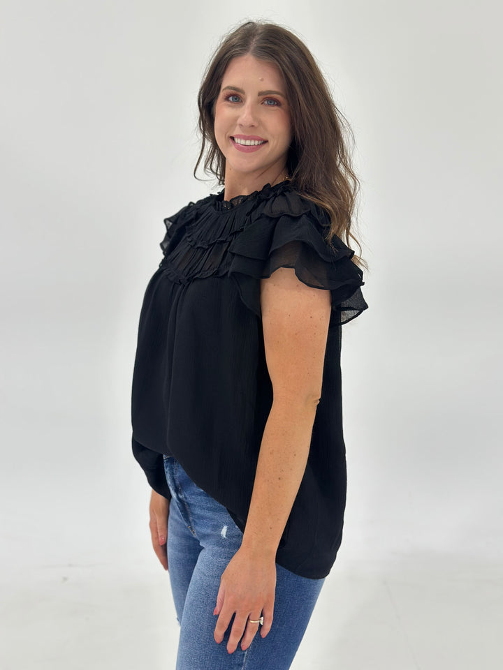 Elevate your wardrobe with this solid chiffon mock-neck blouse, featuring delicate pleats on the front and a soft, flowy shape perfect for day-to-night outfits. The short sleeves and lightweight woven material make it ideal for warmer weather, while the full lining ensures it’s non-sheer and comfortable for all-day wear. A back button closure with an elastic loop adds charm and ease of dressing. Whether you're styling it for the office, brunch, or a weekend dinner, this minimalist top brings quiet sophistic