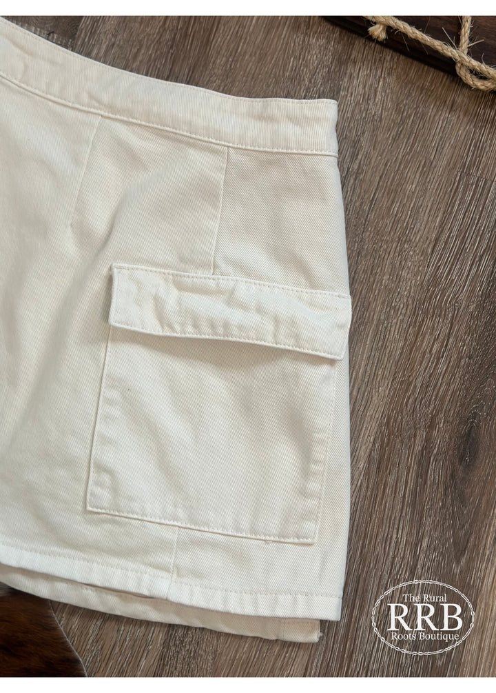 Discover The Logan Skirt, a fashionable off white wrap cargo mini skirt designed for versatility. Featuring a flattering high waist and button closure, this skirt offers a modern twist on classic styles. Made from 74% cotton and 26% polyester, it ensures comfort and a great fit. Available in Small (2-4), Medium (6-8), and Large (8-10), it’s perfect for any occasion.