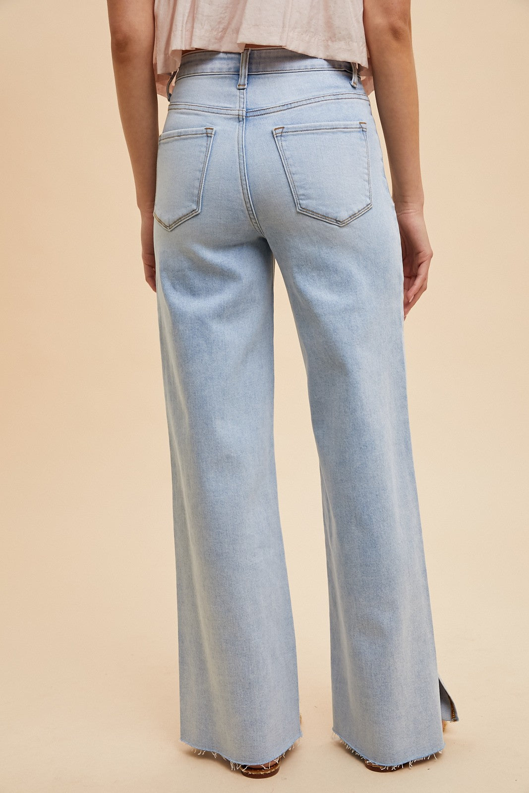 The Sadie High Rise Wide Leg Jeans feature a light wash and a flattering silhouette with a modern wide leg cut. Designed with subtle side slits at the hem, these jeans offer both style and comfort thanks to their stretchy denim blend of 92% cotton, 6% polyester, and 2% spandex. The high rise waistline provides a secure, contoured fit, making them a versatile staple for any casual or dressed-up look.