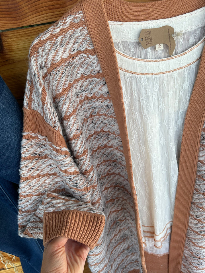 Elevate your wardrobe with The Cedar Creek Contrast Trim Speckled Loop Open Cardigan in Mocha/Natural. This relaxed-fit cardigan features long sleeves and side pockets, making it a practical and fashionable choice for everyday wear. Made from a soft blend of cotton, acrylic, polyester, and nylon, it adds a cozy touch to any look, from casual outings to relaxed evenings at home.