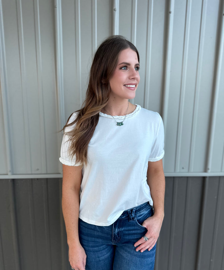 Add a touch of elegance to your summer wardrobe with The Chappell Short Sleeve Top in White. This fashionable top features braided knot trim on the neckline and sleeves, combining comfort and style effortlessly. Made from a soft blend of 95% cotton and 5% spandex, it’s available in sizes small, medium, and large, making it perfect for any casual outing or gathering.