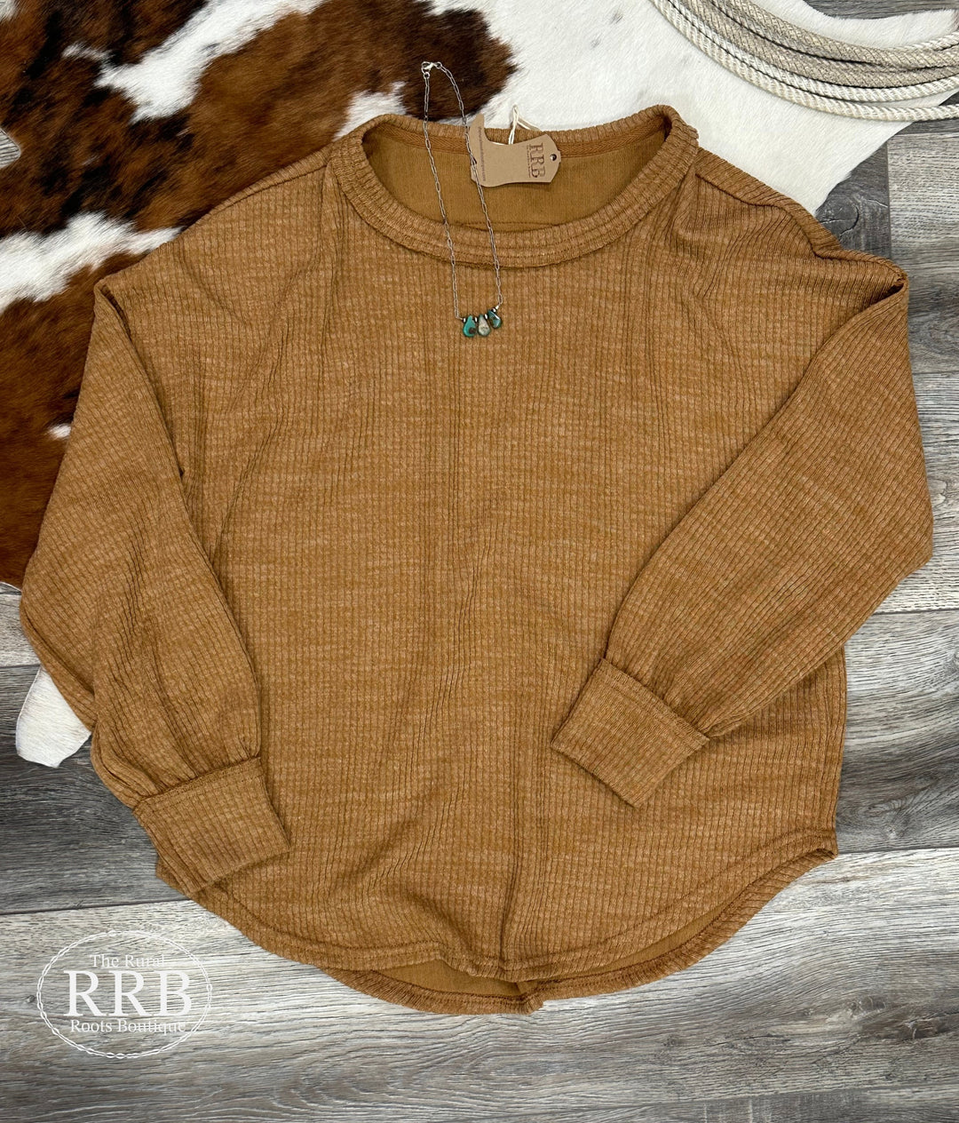 Explore The Crofton Sweater Knit Top in tan, featuring a relaxed fit with a stylish round neckline and long sleeves. Made from a soft blend of 87% polyester, 9% rayon, and 4% spandex, this versatile top is perfect for layering or wearing solo, ensuring comfort and style for any occasion.