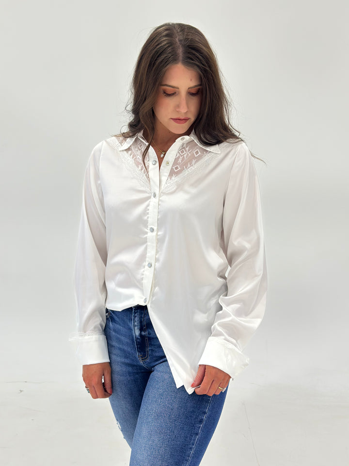 The Elsie Aztec Lace Button Down Shirt in silk features long sleeves, pearl snap closures, and a contemporary fit, adding a touch of elegance to your wardrobe. Available in Small (3-5), Medium (6-8), and Large (9-11).