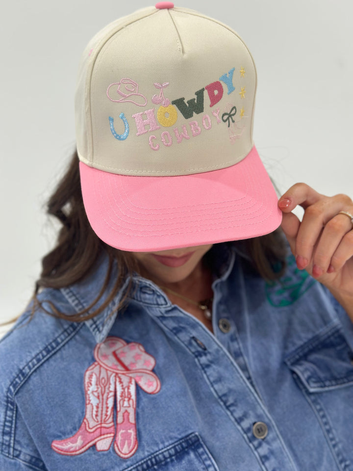 The Howdy Cowboy Pink/Natural Canvas Cap features bold embroidery and an adjustable snapback for a custom fit. Perfect for adding a little cowboy flair to your look!