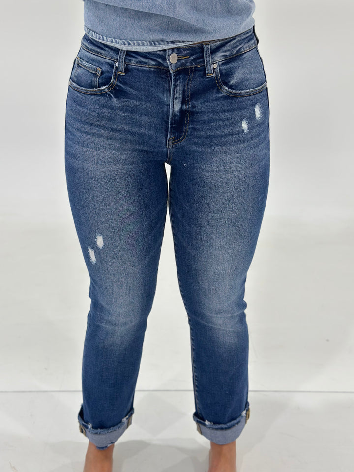 The Koby High Rise Straight Turn Up Jean in medium wash features a distressed look, 5-pocket style, and a cuff that can be released for a versatile fit. Made with 94% Cotton, 4% Polyester, and 2% Spandex for added stretch and comfort.