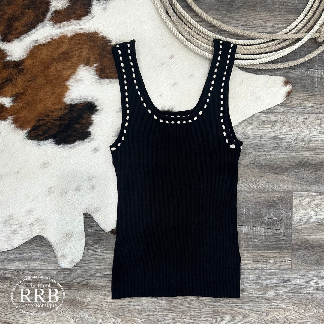 Upgrade your wardrobe with The Lacey Sleeveless Rib Sweater in black, featuring a unique contrast stitch and intricate stitch design around the neck and arms. Made from a comfortable stretch knit blend of 49% viscose, 28% polyester, and 23% nylon, this slightly fitted sweater is perfect for layering or wearing alone. Available in sizes Small (2-4), Medium (6-8), and Large (8-10).