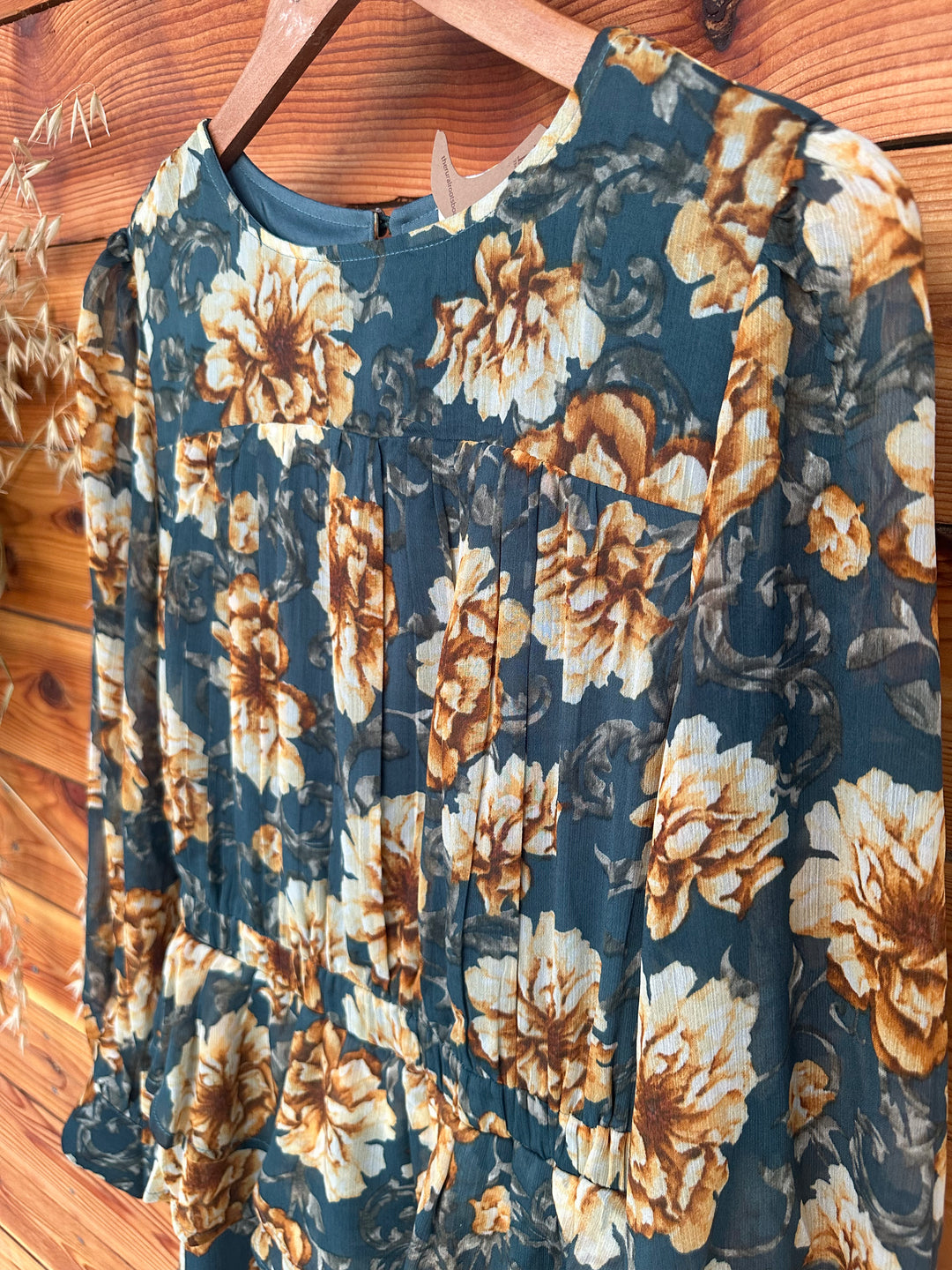 Stylish The Lola teal floral print chiffon dress featuring a layered skirt design, round neckline, and keyhole back with button closure. This dress includes long sleeves with buttoned cuffs, pleated shoulders, and an elastic waist for added comfort. Fully lined and made from 100% polyester, available in sizes Small (3-5), Medium (6-8), and Large (9-11). A chic alternative to similar dresses from Boohoo and PrettyLittleThing.