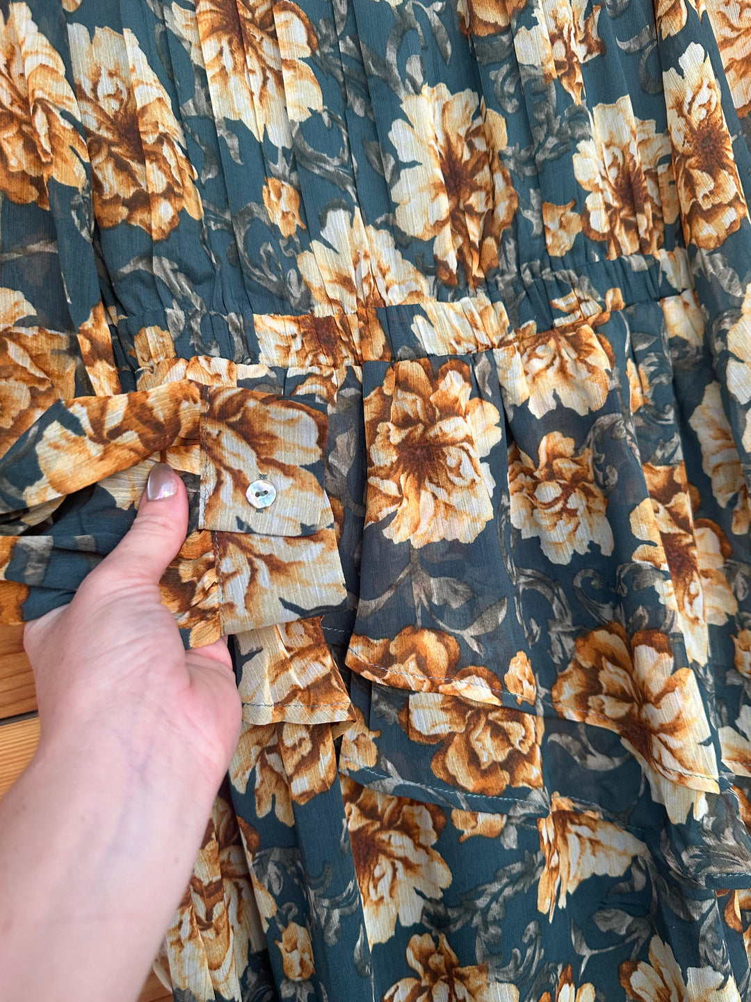 Chic The Lola teal floral print chiffon dress with a layered skirt, featuring a round neckline, keyhole back with button closure, and long sleeves with elegant buttoned cuffs. The dress includes pleated shoulders, an elastic waist, and is fully lined for comfort. Crafted from 100% polyester, available in Small (3-5), Medium (6-8), and Large (9-11). A stylish choice for any occasion, comparable to designs from Zara and H&M.