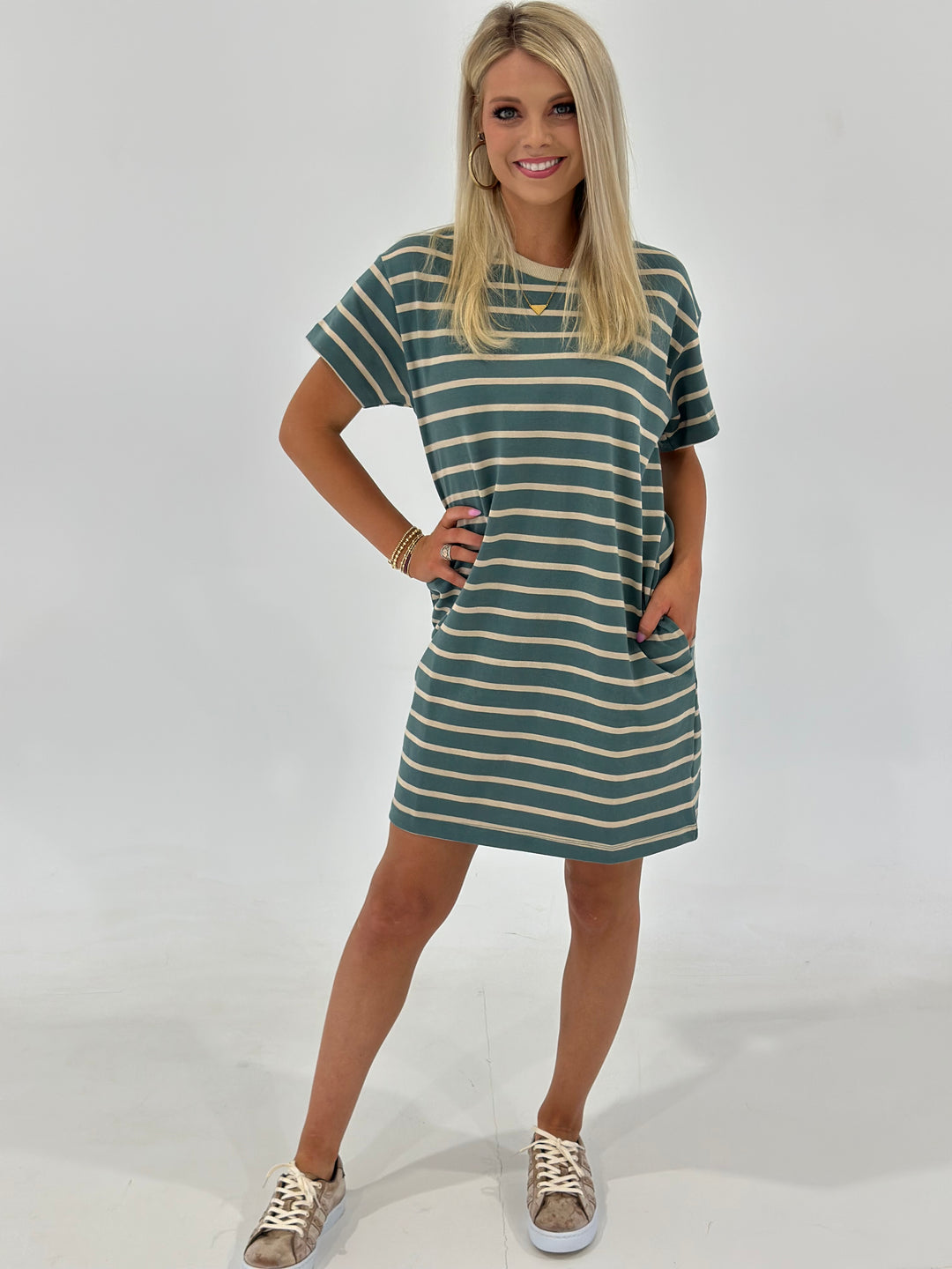 The Looms Striped T-Shirt Mini Dress in Teal/Taupe is made from 100% cotton for a comfortable fit, featuring side pockets and a casual, relaxed vibe. Available in Small (2-4), Medium (6-8), and Large (9-11).