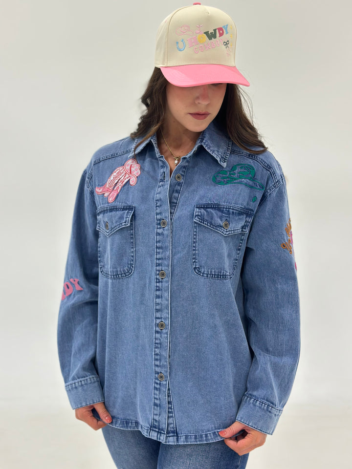 The Marigold Embroidery Denim Button Down features a fun "Hat, Boot, and Giddy Up" embroidery, long sleeves, and a relaxed fit. Perfect for casual wear with a touch of western flair. Available in Small (3-5), Medium (6-8), Large (9-11), and X-Large (12-14).