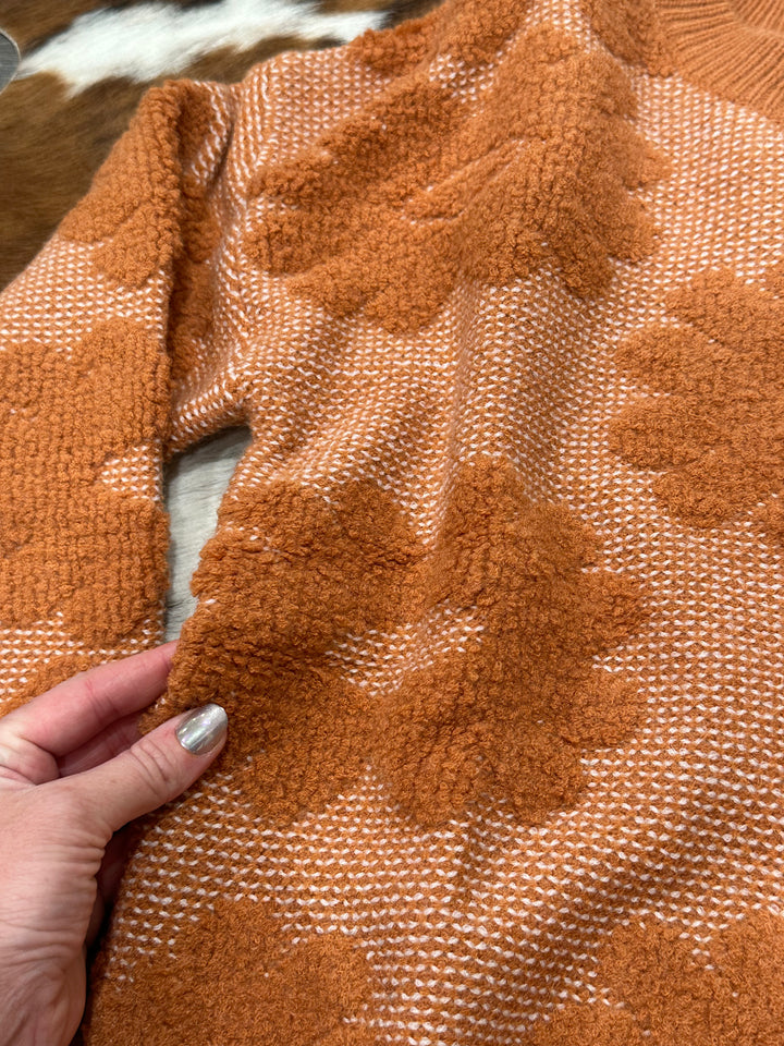 Warm and cozy Marlow rust-colored floral knit sweater with a relaxed fit, perfect for cooler days. Available in sizes Small (3-5), Medium (6-8), and Large (9-11), this sweater makes a versatile addition to any wardrobe. Comparable to cozy knits from Urban Outfitters and Everlane.