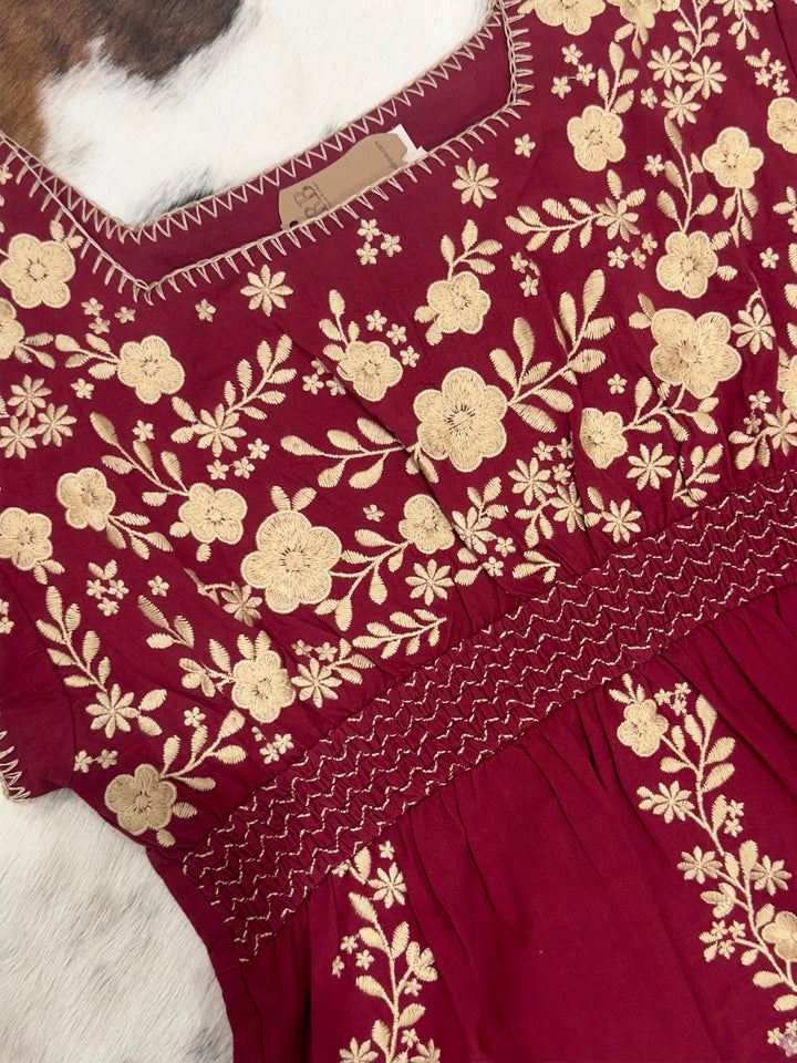 Chic The Perryn tunic top in wine, adorned with beautiful floral embroidery and a square neckline. Crafted with short sleeves and non-sheer material, this top is a stylish option for casual outings. Available in Small (3-5), Medium (6-8), and Large (9-11) to fit your style.