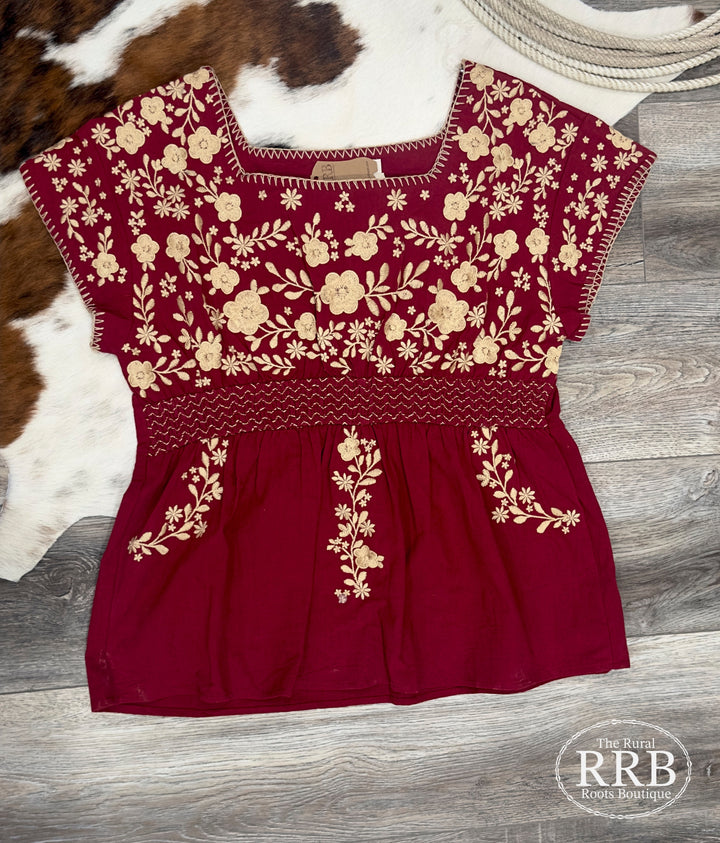 Beautiful The Perryn tunic top in rich wine color, featuring delicate floral embroidery and a flattering square neckline. Designed with short sleeves and non-sheer fabric, this top offers comfort and style. Available in Small (3-5), Medium (6-8), and Large (9-11) for a versatile addition to your wardrobe.