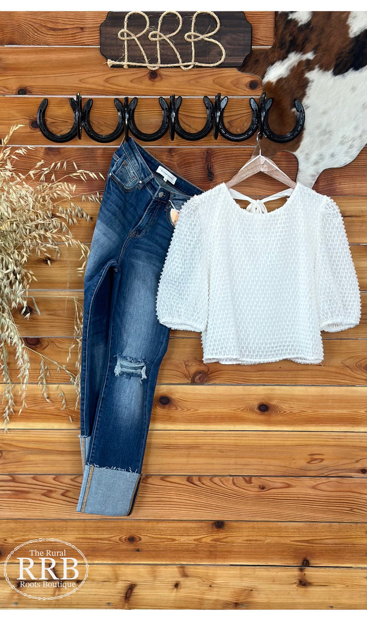 Embrace elegance with The Roslyn textured top in ivory, featuring charming puff sleeves and a stylish tied back. This versatile piece is perfect for any occasion and is available in Small (2-4), Medium (6-8), and Large (8-10) for a flattering fit.