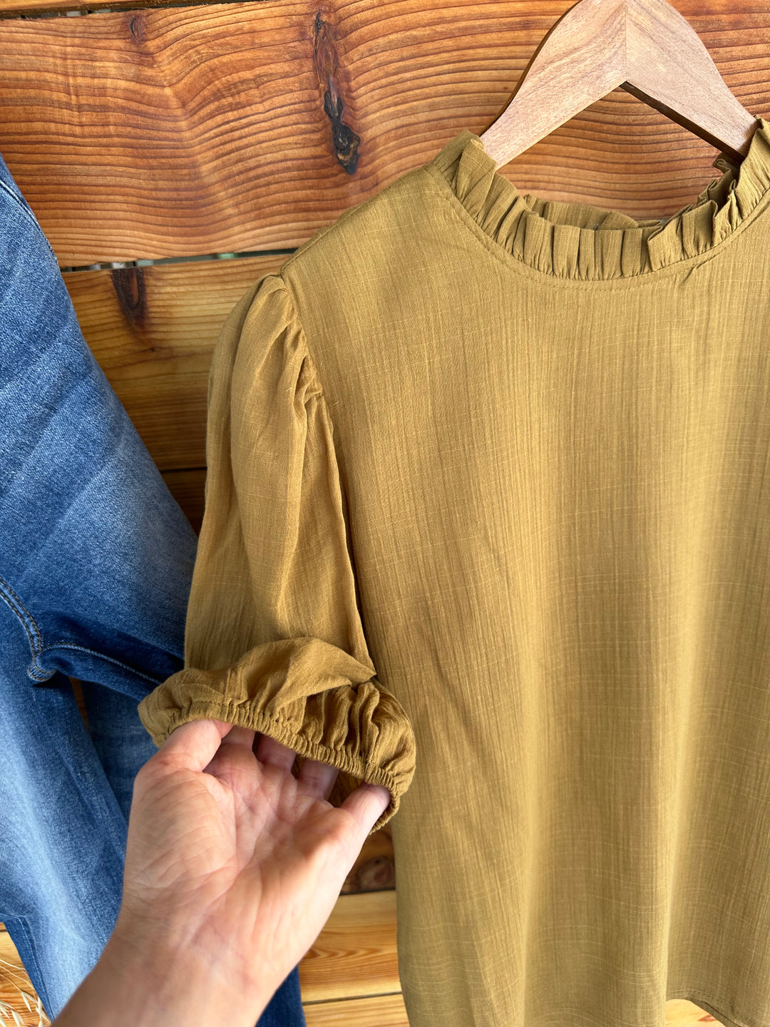 Step into style with The Woodland shirt, featuring a textured ruffle neck and elegant puff sleeves with elastic at the cuffs. This cotton top in moss color includes a stylish tie waist with self strap, perfect for accentuating your silhouette. True to size fit in Small, Medium, and Large.