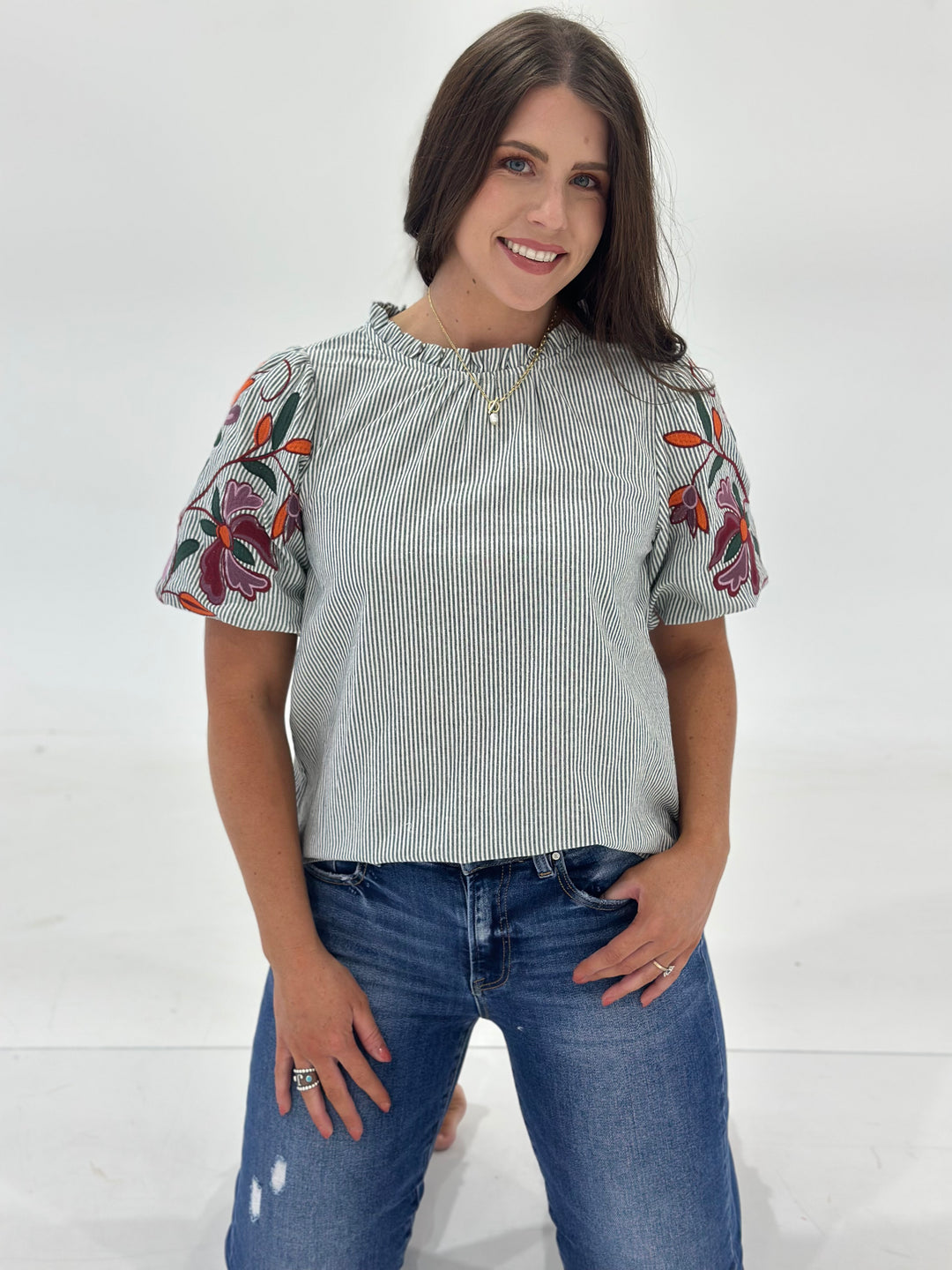 This women’s striped blouse features delicate floral embroidery across the front, adding a soft, feminine touch to the classic short sleeve top. Designed with a round neckline and subtle ruffle detail, this woven shirt offers a flattering and versatile silhouette that works for casual daywear, office outfits, or dressed-up occasions. The lightweight woven fabric ensures breathable comfort, while the elastic loop button closure at the back of the neck adds a touch of charm and functionality. With horizontal 